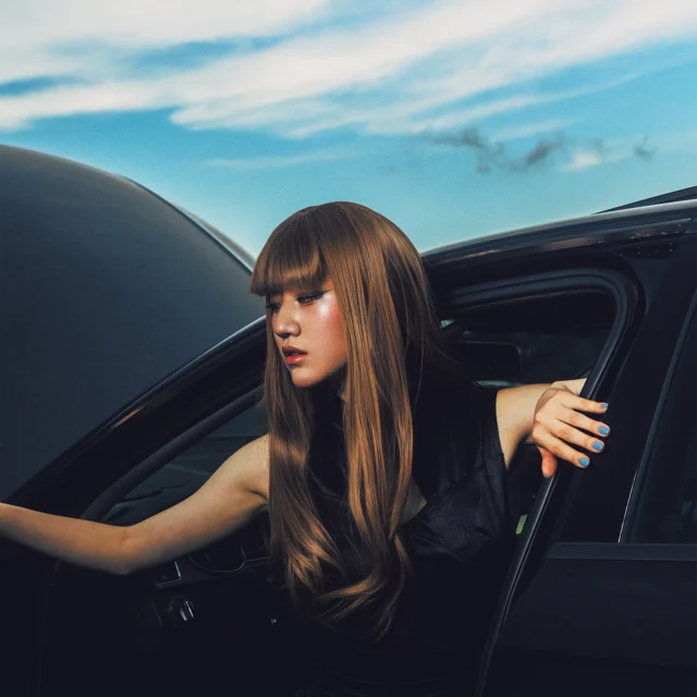 Creator Shroomish.cos cosplay in black dress posing in front of Audi outdoors under the blue sky.