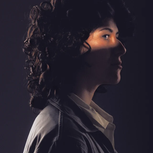 Ellen Ripley cosplayer from the movie Alien posing in dramatic and ominous lighting looking into the distance.