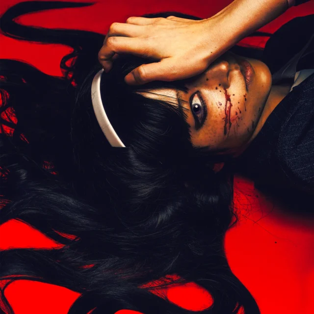 Tomei from Junji Ito cosplay with blood on her cheek on red background by influencer me.bigboy in haunting, horror editorial portrait.